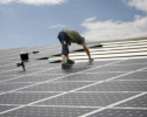 Panneaux solaires posés par une personne sur un toit en pente
