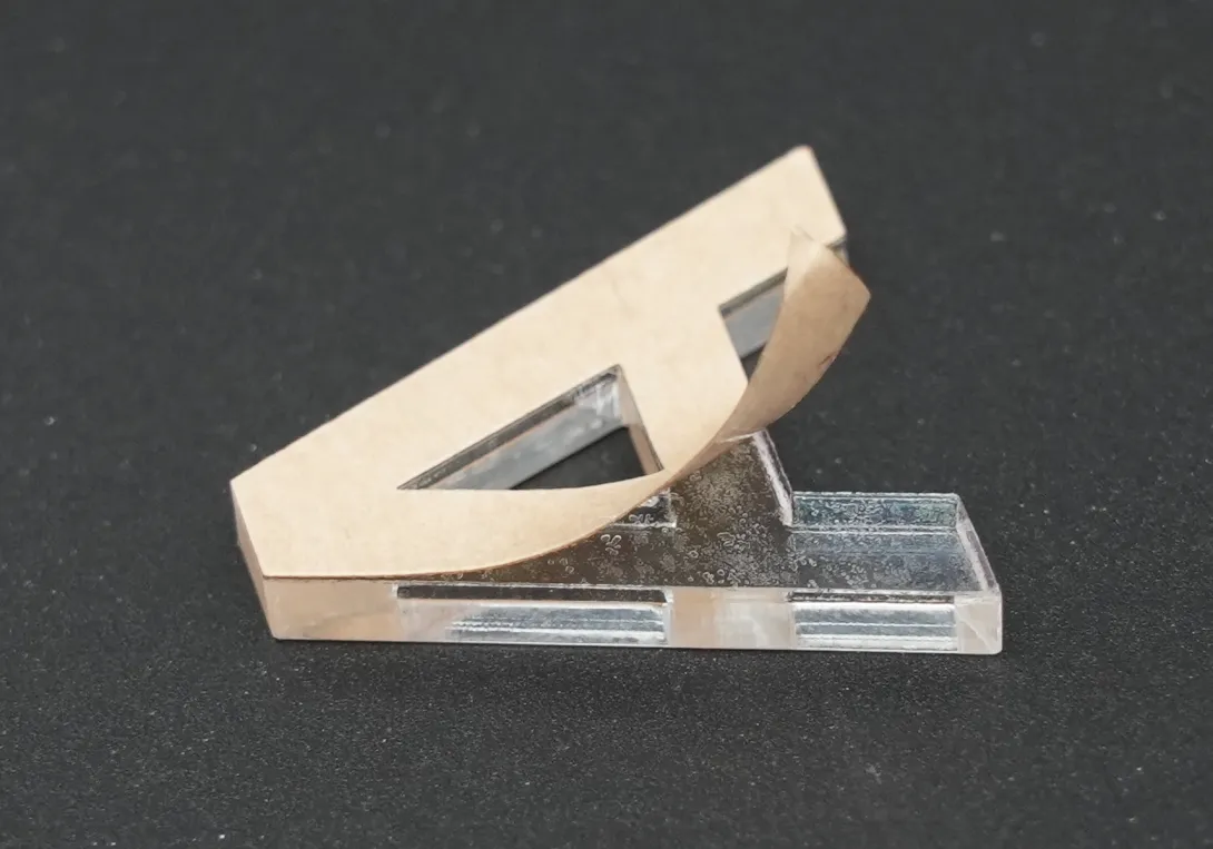 Découpe au laser d'une surface en PMMA sur laquelle est collée du ruban adhésif 3M 9629